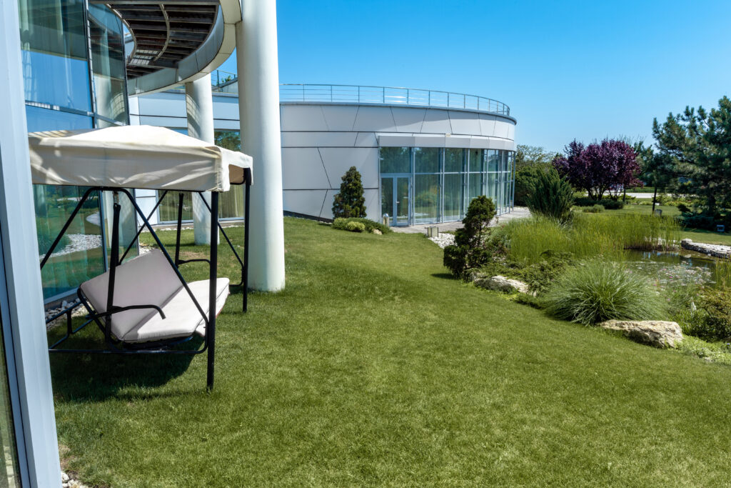 Lush green lawn with a swing chair beside a modern building, showcasing professional lawn installation services for residential and commercial spaces.