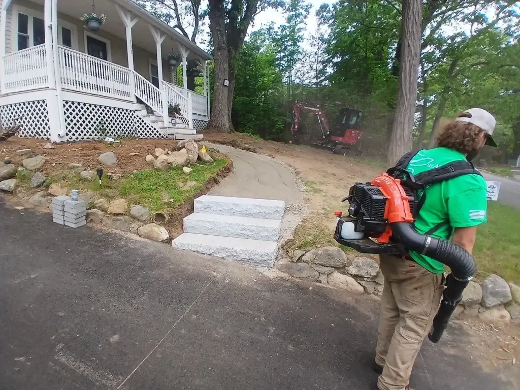 Cut Above Landscaping worker blowing leaves on Lexington custom home landscape project.