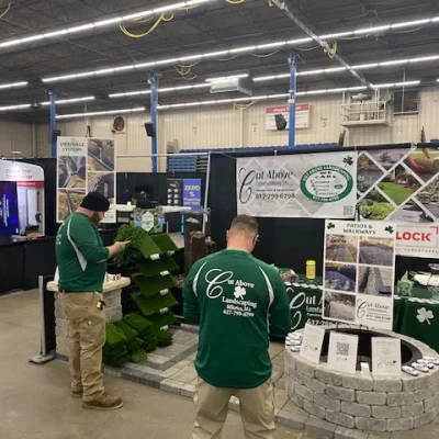 Cut Above Landscaping Inc. display booth at home show featuring patios, artificial turf, and Unilock pavers.