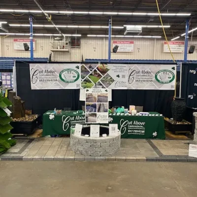 Cut Above Landscaping Inc. display booth with Unilock pavers, Aquascape fountain, and promotional materials at a home show.
