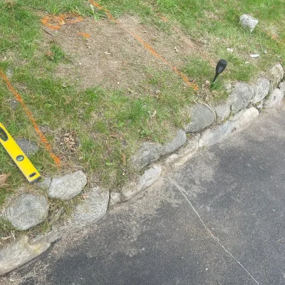Granite stone wall and paver walkway preparation with level, Cut Above Landscaping project.