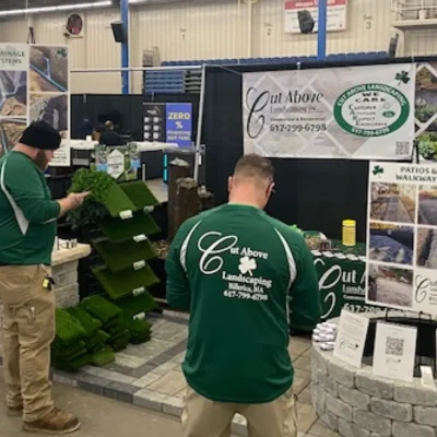 Cut Above Landscaping Inc. booth display at suburban Boston home show featuring artificial turf and paver samples.